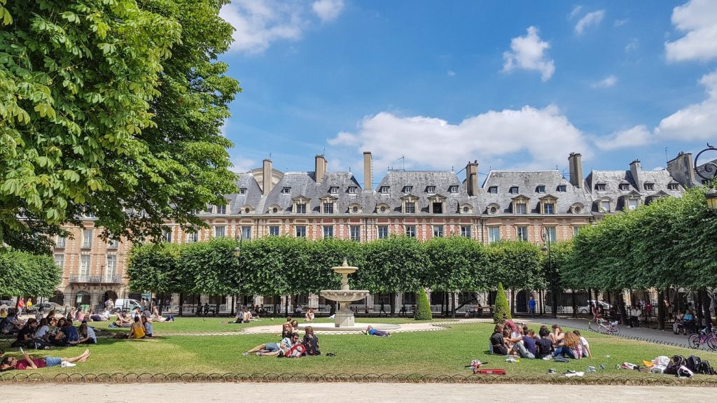 Mensen picknicken in het park van Place des Vosges in de wijk Le Marais in Parijs