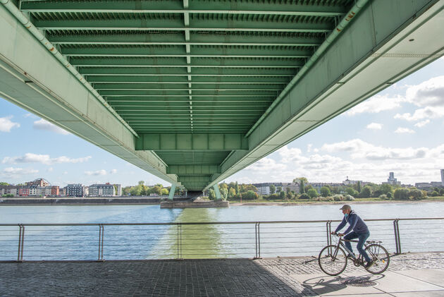 Een fietser neemt het pad langs de oever onder de Severinsbr\u00fccke door