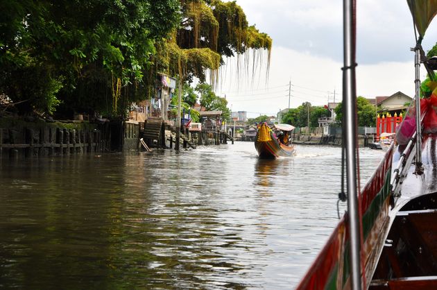 We varen over de Chao Phraya-rivier door de buitenwijken van de stad
